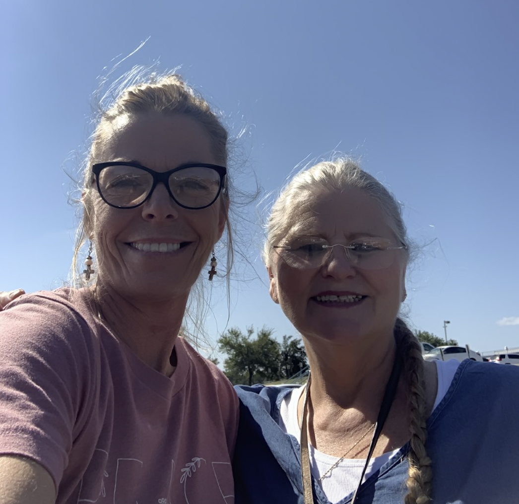 Two women smiling with a clear blue sky behind them