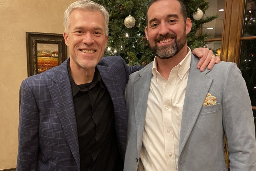 Two men standing in front of a Christmas tree smiling at the camera